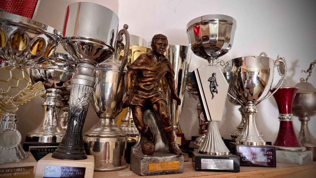 Curley Park Rangers FC trophy collection with bronze player statue